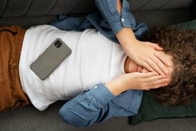 Mann liegt und h&auml;lt sich schmerzhaft den Kopf &ndash; Symbolbild f&uuml;r chronische Schmerzen und medizinische Cannabis-Behandlung
